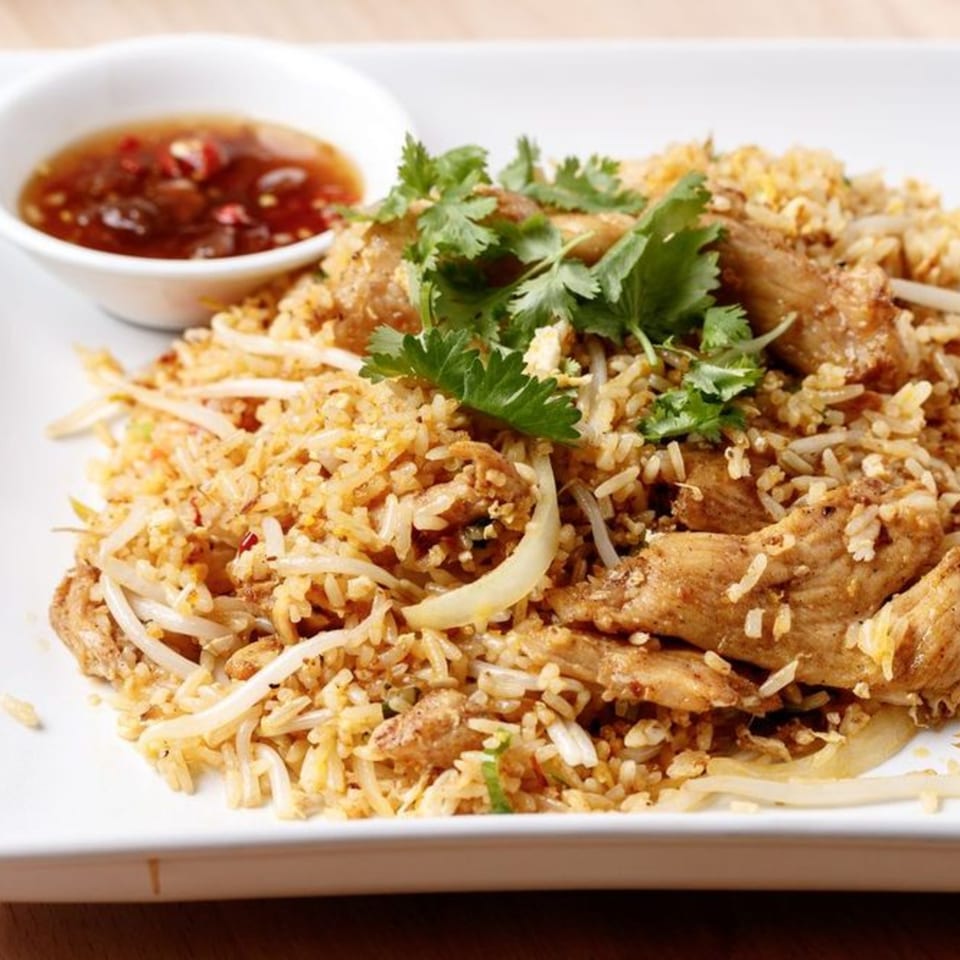 Vietnamese fried rice with chicken, bean sprouts, onions, and cilantro, served with chili sauce.